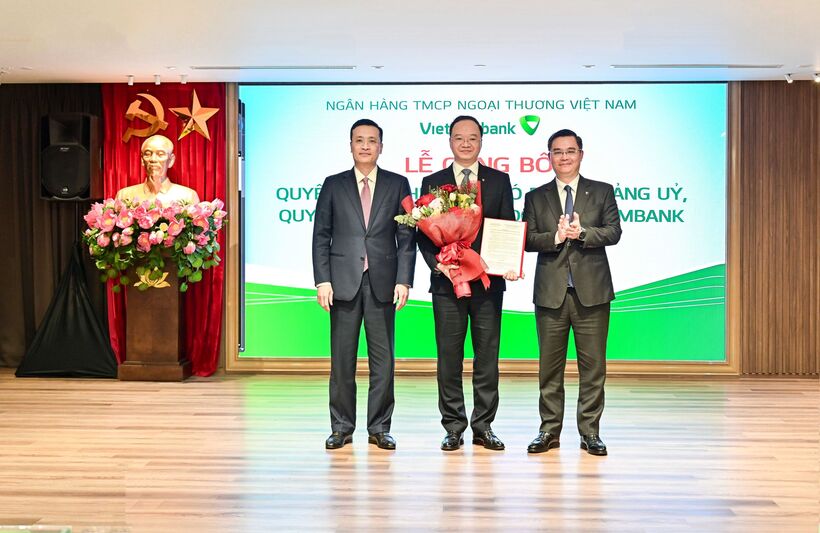 Đ/c Phạm Quang Dũng - Ủy viên Ban Thường vụ Đảng ủy, Phó Thống đốc NHNN (ngoài cùng bên trái) và đ/c Nguyễn Thanh Tùng - Ủy viên BCH Đảng bộ Chính phủ, Bí thư Đảng ủy, Chủ tịch HĐQT Vietcombank (ngoài cùng bên phải) trao quyết định và tặng hoa chúc mừng đ/c Lê Quang Vinh - tân Tổng Giám đốc Vietcombank