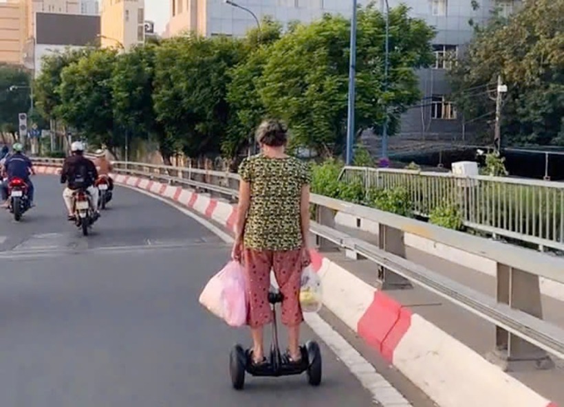 Hình ảnh người phụ nữ đi xe điện cân bằng trên cầu Khánh Hội. (Ảnh: SGGP)