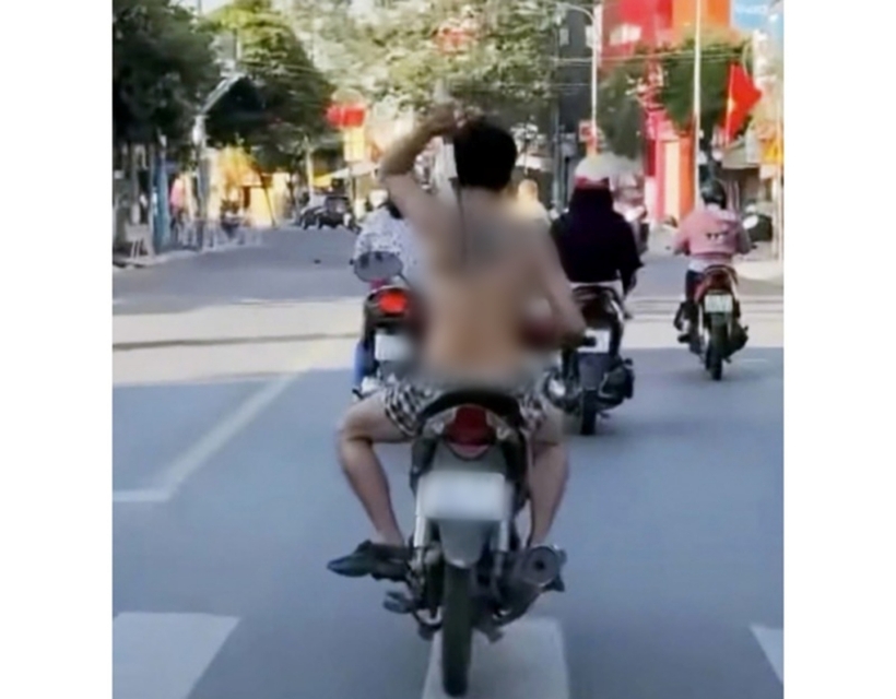 Người đàn ông đi xe máy, cởi trần, không đội mũ bảo hiểm và "múa" rựa loạn xạ trên đường. Ảnh: Công An Nhân Dân