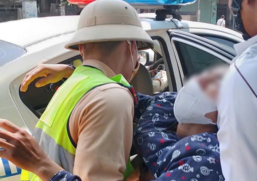 CSGT đưa người phụ nữ lên ô tô chuyên dụng, chở tới bệnh viện cấp cứu. Ảnh: VnExpress
