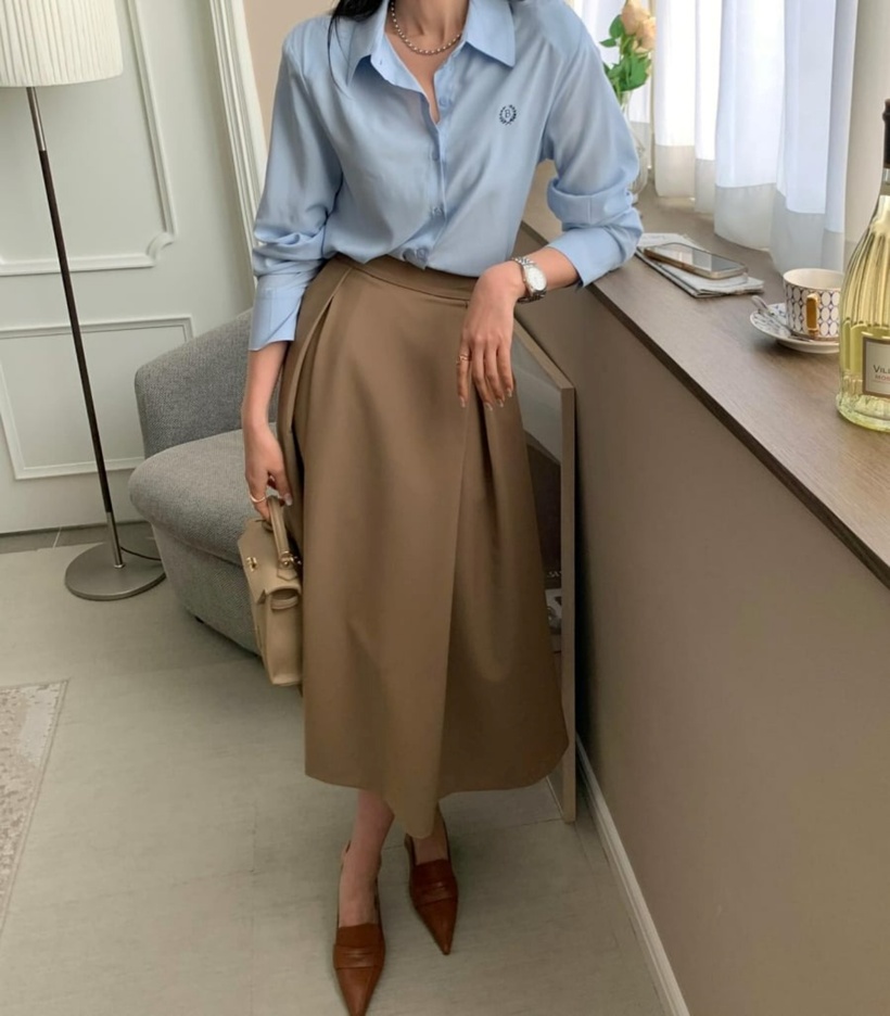 Áo sơ mi màu xanh pastel mang đến nét trẻ trung và dịu dàng cho người mặc. Nhờ vào sự nổi bật của màu sắc này, phái đẹp có thể phối hợp với chân váy chữ A màu be để tạo sự hài hòa cho tổng thể trang phục. Đôi giày mũi nhọn màu nâu không chỉ giúp tôn dáng mà còn thêm phần tinh tế, làm nổi bật vẻ sang trọng cho cả bộ đồ.