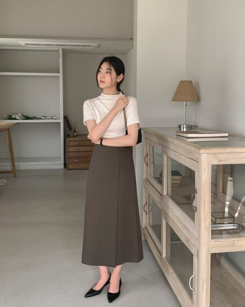 Một lựa chọn đơn giản nhưng sang trọng cho các bạn nữ nơi công sở chính là sự kết hợp giữa áo thun và chân váy xếp vạt. Với bộ trang phục này, đôi giày mũi nhọn sẽ làm nổi bật lên phong cách tinh tế và giúp ăn gian chiều cao một cách khéo léo. Để tạo nên sự hài hòa cho tổng thể outfit, phái nữ nên lựa chọn một chiếc túi xách màu đen, vừa thời trang vừa dễ dàng phối hợp.