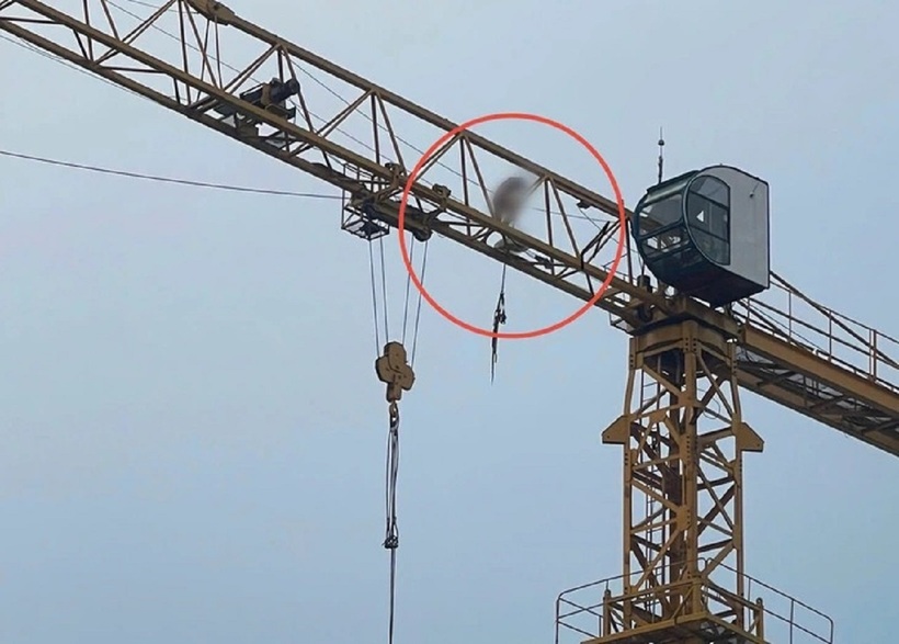 Người đàn ông không mặc quần áo "làm xiếc" trên cần cẩu cao hàng chục mét. Ảnh: Tuổi Trẻ