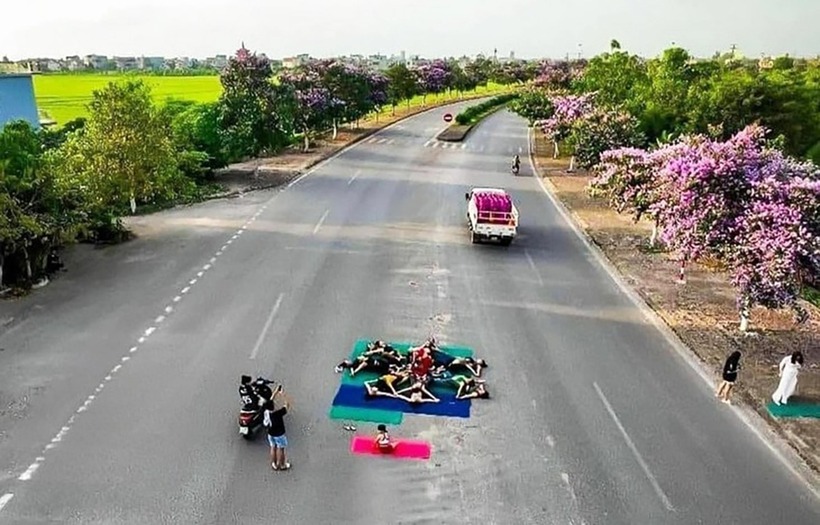 Nhóm phụ nữ mặc áo bó sát, quần legging, trải thảm giữa Quốc lộ 37 để tập yoga. Ảnh: VOV.