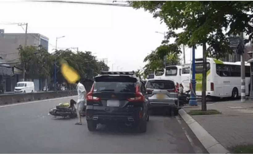 Tài xế ô tô mở cửa xuống xe khiến một người đàn ông chạy xe ôm công nghệ va phải, ngã xuống đường. Ảnh: Tuổi Trẻ Online