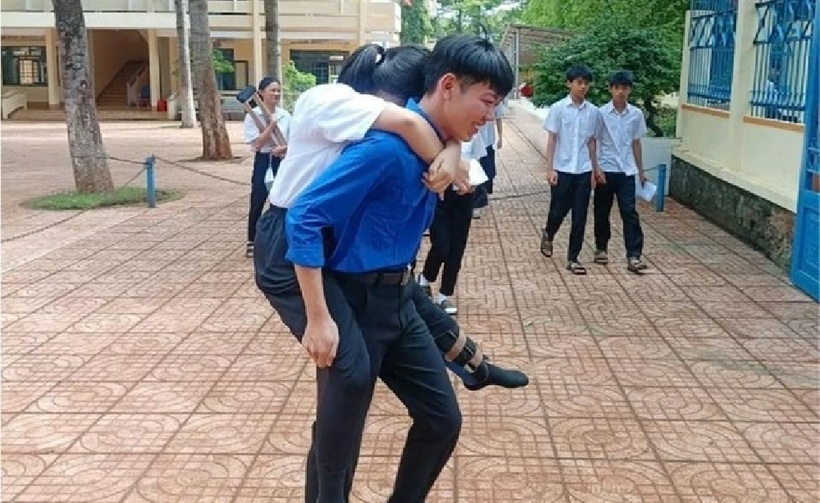 Nam sinh áo xanh tình nguyện cõng một thí sinh vào phòng thi. Ảnh: Báo Lao động.