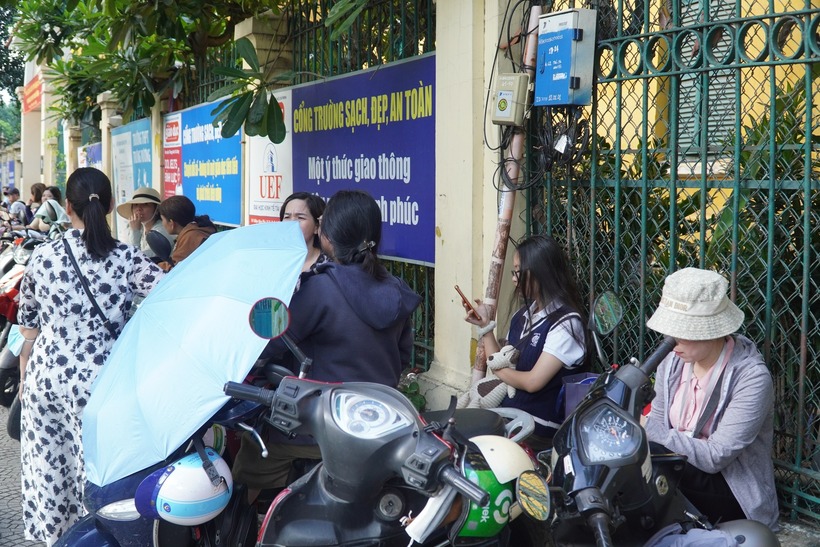 Không về nhà, nhiều phụ huynh mang theo dù, váy chống nắng, cắm trại tại điểm thi trong suốt 120 phút làm bài.