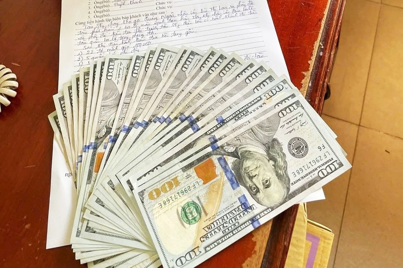 Trong ba lô bị bỏ quên có 22 tờ tiền mệnh giá 100 USD cùng nhiều tờ báo, tài liệu học tiếng Anh. (Ảnh: Dân trí)