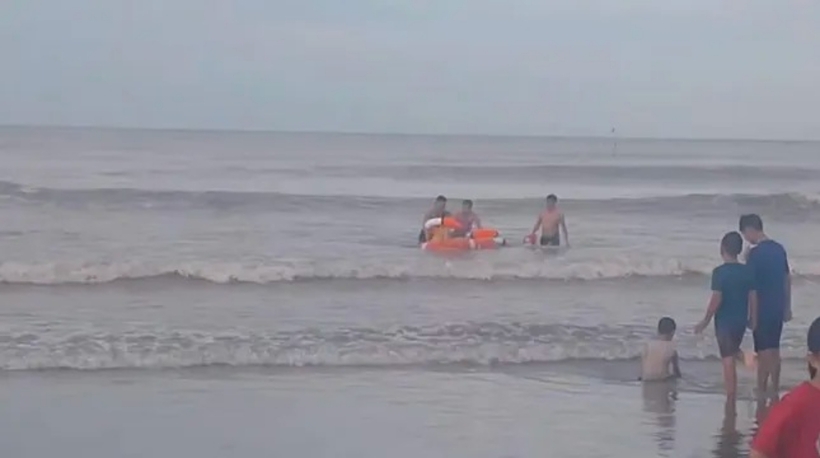 Đại úy Hoàng Văn Bé - Trưởng Công an thị trấn Lộc Hà và 2 người khác mang theo phao lao xuống biển cứu bé trai 13 tuổi, đưa vào bờ an toàn. Ảnh: Tiền Phong