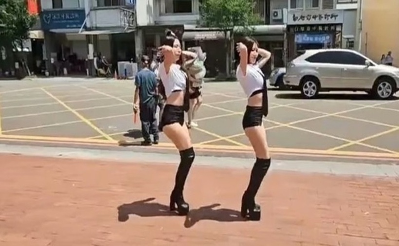 Hai vũ công ăn mặc gợi cảm được thuê múa cột trước cổng trường.