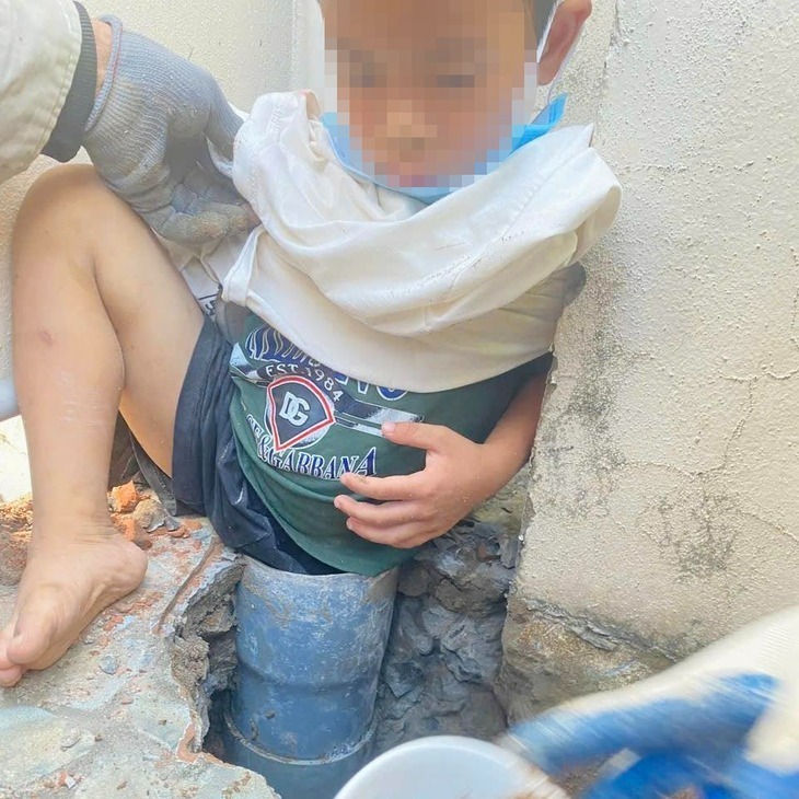 Bé trai bị kẹt chân vào ống thoát nước dưới nền sân. Ảnh: Báo Tuổi trẻ.