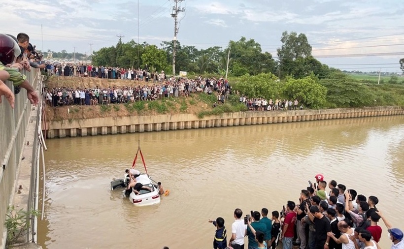 Người dân theo dõi lực lượng chức năng trục vớt ô tô rơi xuống sông khi qua xã Vạn An, Nghệ An chiều 13/7. (Ảnh: Tuổi trẻ)