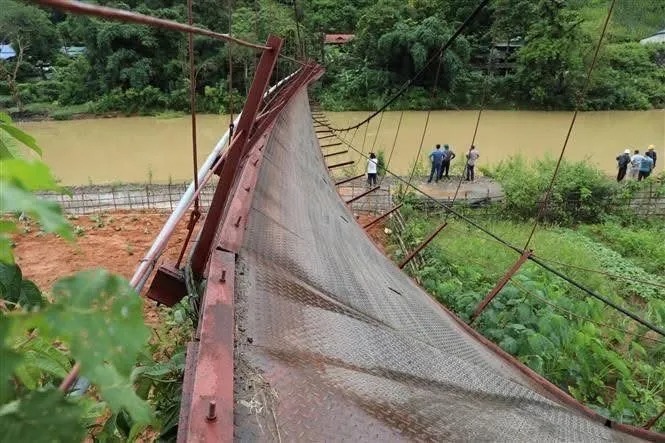 Chiếc cầu treo bị đứt cáp, lật nghiêng. (Ảnh: SGGP)