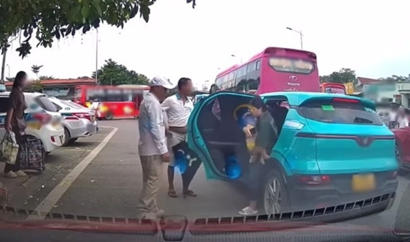 Nhóm người chặn taxi công nghệ đón khách, đuổi người phụ nữ bế con nhỏ ra khỏi xe. Ảnh: Lao động