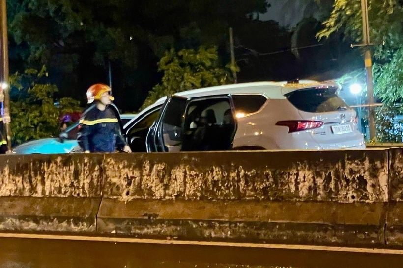 Cảnh sát đội mưa, dập tắt đám cháy ô tô. Ảnh: Dân trí