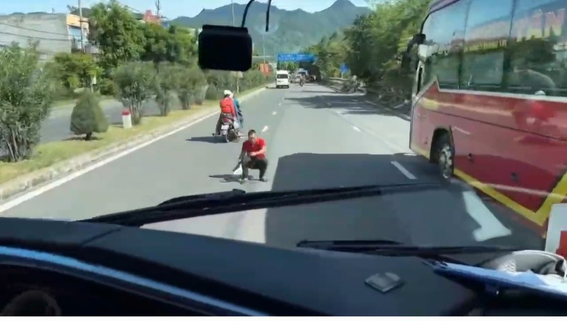 Người đàn ông ngồi giữa QL1 chặn đứng các phương tiện đang lưu thông gây rối loạn giao thông. (Ảnh: Thanh niên)