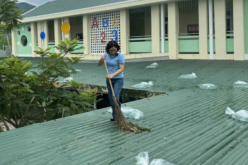Nữ giáo viên mầm non ở Huế leo lên gia cố, vệ sinh mái tôn trường học để phòng, chống bão số 5. Ảnh: Dân trí