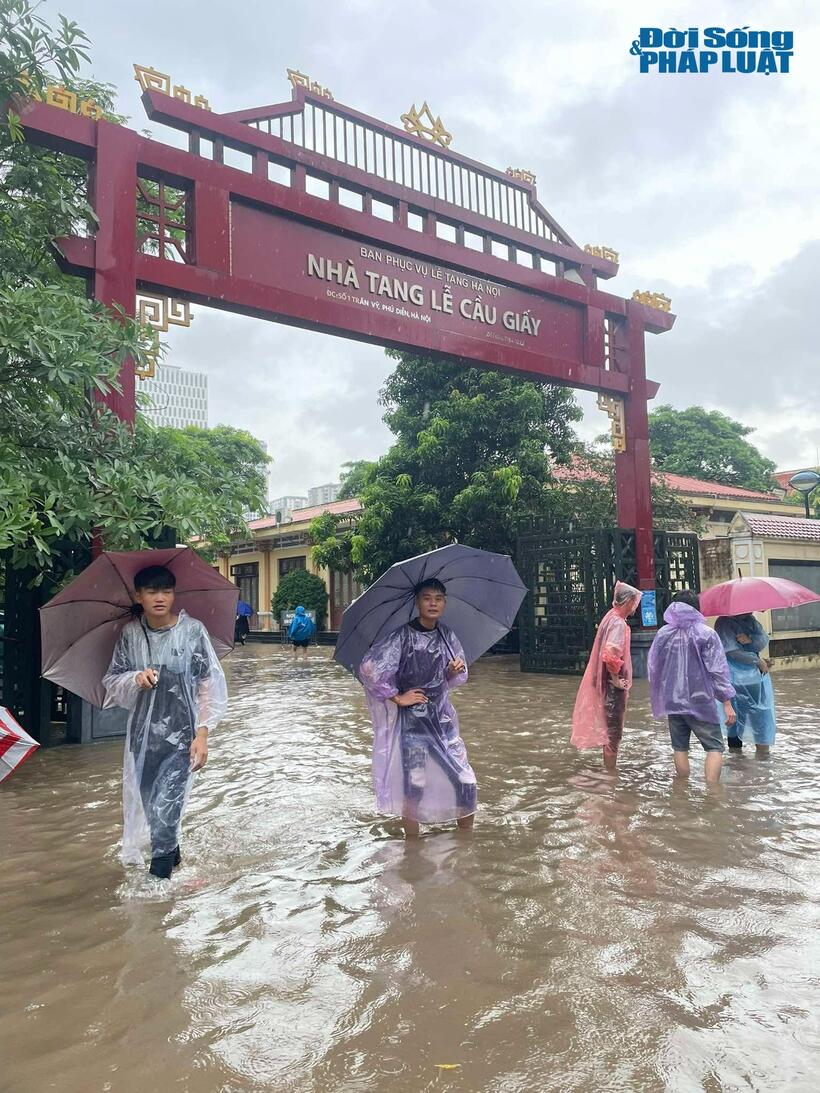 Tình hình cũng không khá hơn tại khu vực Nhà tang lễ Cầu Giấy, nơi nước ngập đến bắp chân, người dân phải bì bõm lội nước.