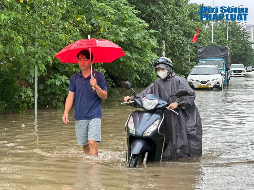 Tại khu vực đường Hồng Đô (phường Từ Liêm), một cô gái phải dắt bộ chiếc xe máy bị chết máy giữa dòng nước ngập. Các tuyến đường khác như Nguyễn Văn Trỗi, Phương Liệt cũng rơi vào tình trạng tương tự.