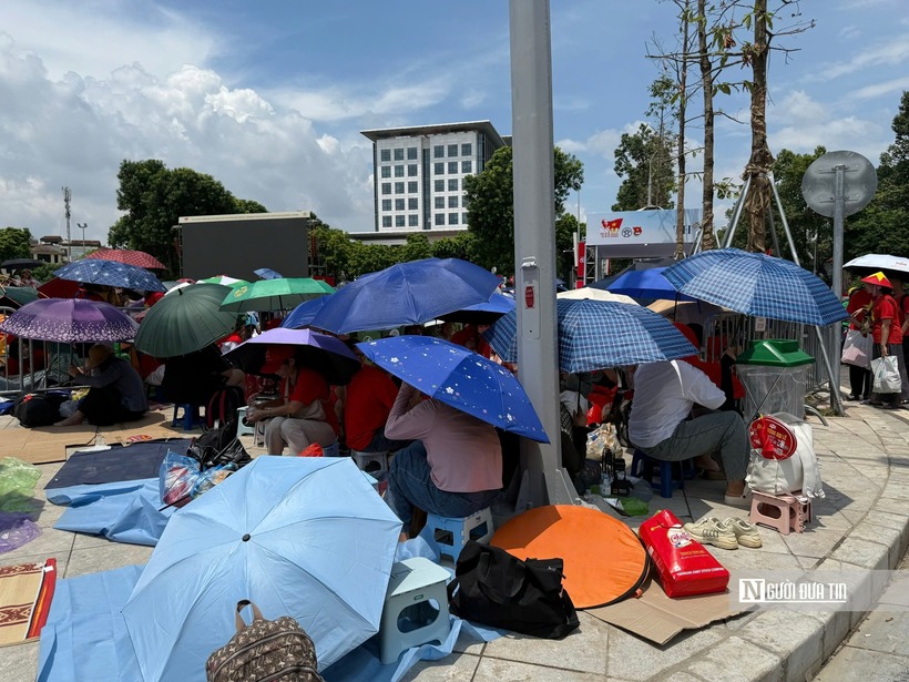 Rất đông người dân đội nắng, đội mưa che ô giữ chỗ chờ xem tổng duyệt diễu binh, diễu hành A80. Ảnh: Hoàng Bích