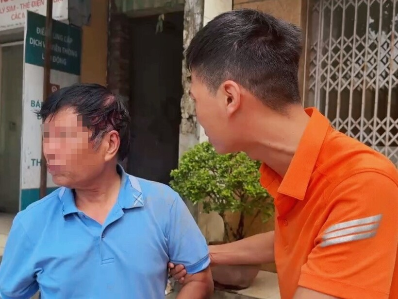 Đại uý Nguyễn Kim Lợi (áo cam) hỗ trợ người đàn ông bị thương ở đầu khi ngã xe.