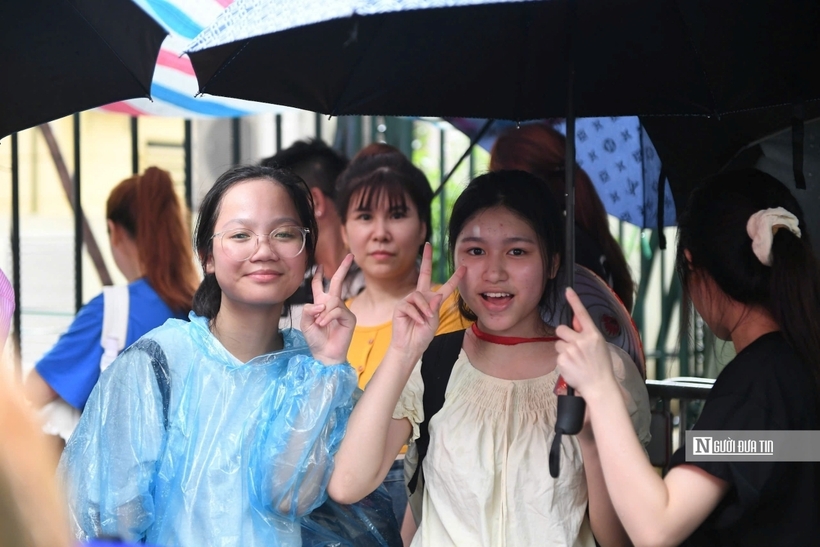 Các bạn trẻ mặc áo mưa và tranh thủ chụp ảnh kỷ niệm.