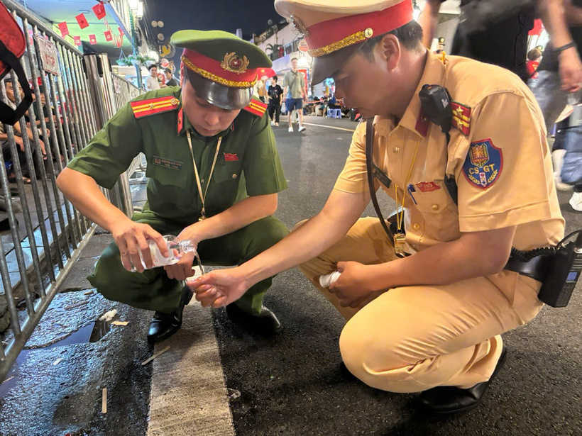 Một đồng chí CSGT dùng tay ngăn chặn người phụ nữ có nguy cơ cắn vào lưỡi gây nguy hiểm
