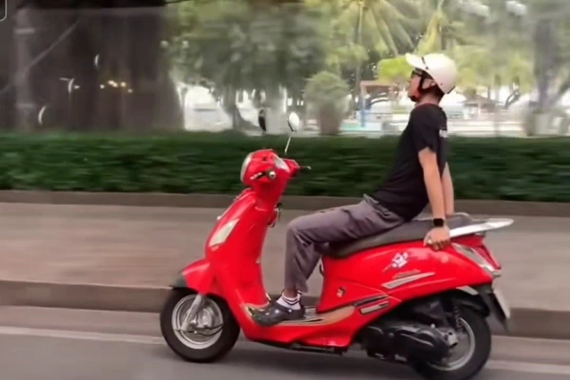 Người đàn ông buông cả 2 tay và ngả người ra sau khi đang lái xe máy trên đường phố Nha Trang. Ảnh: Dân Trí.