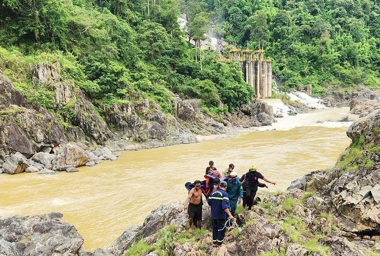 Lực lượng cứu hộ cùng người dân đưa thi thể nạn nhân lên bờ. (Ảnh: Tiền phong)