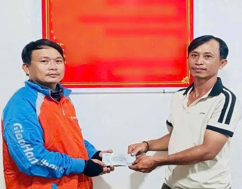 Thợ sửa xe máy Đinh Công Bình (36 tuổi, ngụ Tây Ninh) áo thun trắng bàn giao 30 triệu đồng cho người đánh rơi. (Ảnh: Dân Việt)