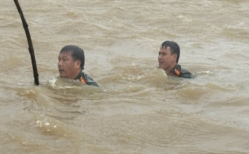 Hai cán bộ Công an xã Nam Cửa Việt dầm mình trong nước lũ tìm chiếc xe bị nước lũ cuốn. (Ảnh: Công an xã Nam Cửa Việt)