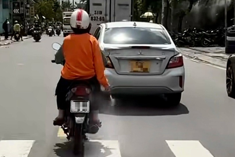 Hình ảnh người phụ nữ ngồi sau xe máy rải "bột lạ" trên đường ở TP.HCM. Ảnh: Dân Trí