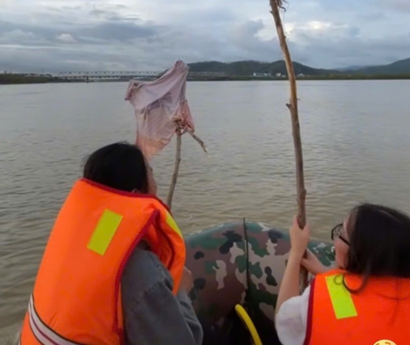 Hình ảnh người mẹ mang theo áo con, ngồi trên ca nô đi dọc sông Lam tìm kiếm con. Ảnh: Vietnamnet