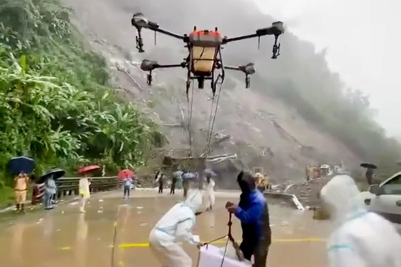 Lực lượng cứu hộ cùng người dân sử dụng drone tiếp tế nhu yếu phẩm cho tài xế mắc kẹt trên đèo Lò Xo. (Ảnh: Dân trí)
