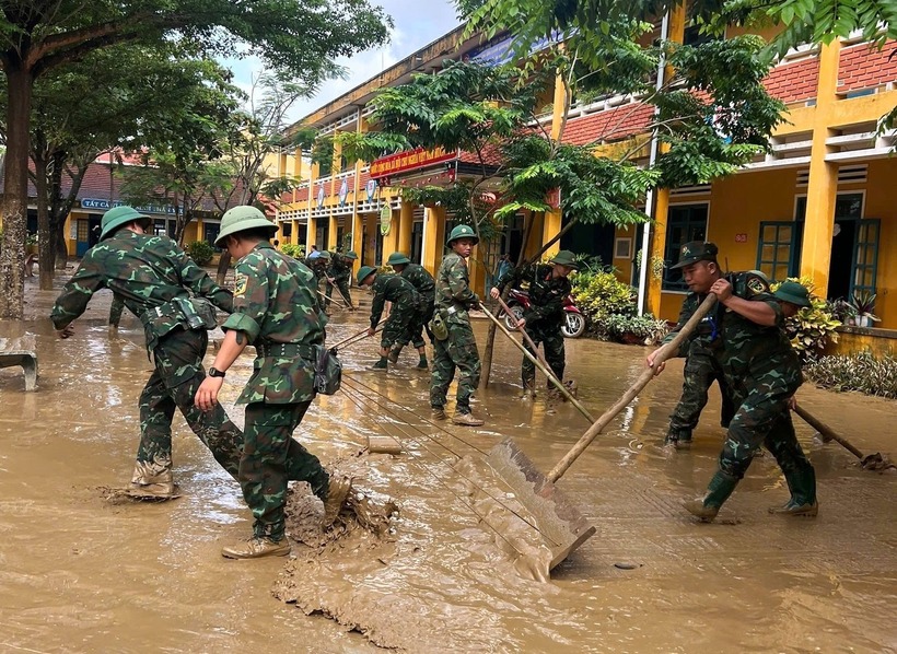 Các chiến sĩ dọn dẹp bùn, làm sạch sân trường để học sinh sớm quay lại lớp.