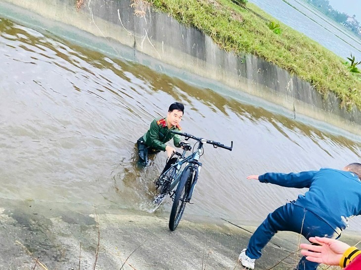 Thượng úy công an kịp thời ứng cứu nam sinh lớp 5 và chiếc xe đạp bị gió thổi rơi xuống kênh. Ảnh: Tuổi trẻ Online