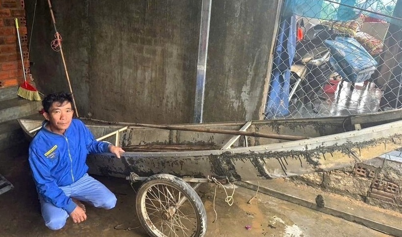 Anh Thành bên chiếc ghe cắt cỏ của gia đình. (Ảnh: VietnamNet)