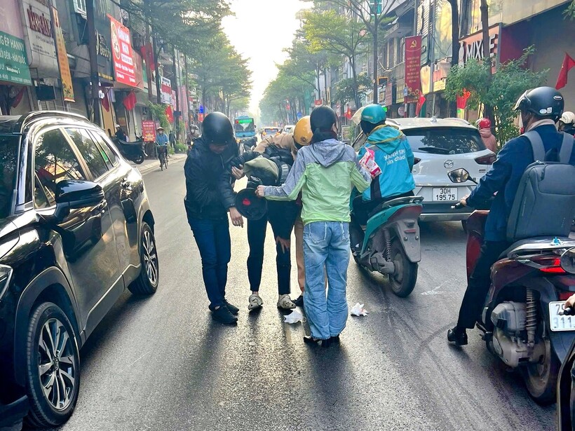 Cảnh sát và người dân hỗ trợ người đi xe máy bị trượt ngã.