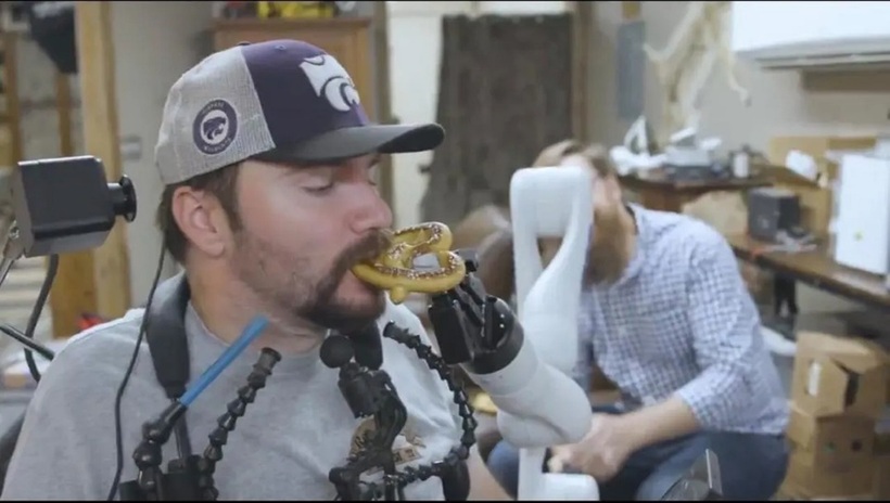 Một bệnh nhân dùng ý nghĩ để điều khiển cánh tay robot đưa thức ăn vào miệng. Ảnh: Neuralink.