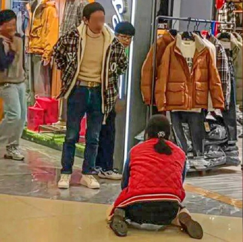 Người phụ nữ quỳ trên sàn, cầu xin chồng mua cho mình chiếc áo khoác lông vũ giá 299 nhân dân tệ. Ảnh: SCMP.