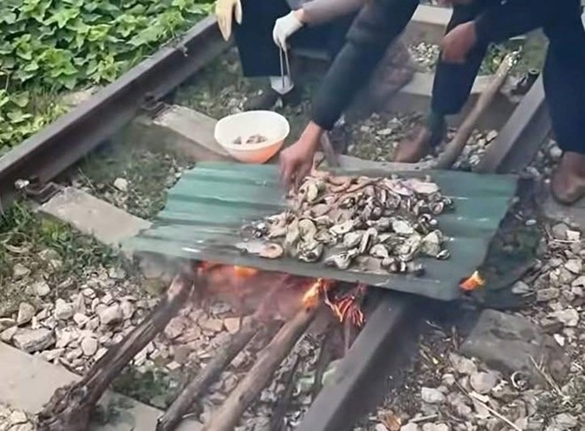 Clip ghi lại cảnh người dân đang nấu nướng thực phẩm trên đường tàu. Ảnh: Lao động