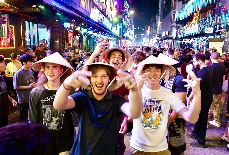 Nhóm du khách người Anh đội nón lá Việt Nam chào đón ngày đầu tiên của năm 2026 trên phố Bùi Viện (TP.HCM). (Ảnh: Tuổi trẻ).