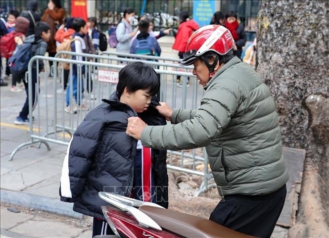 Trẻ em được giữ ấm khi lưu thông bằng xe máy. (Ảnh: TTXVN)