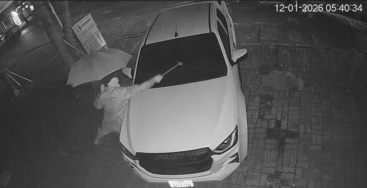 Hình ảnh người đàn ông che ô, bịt kín mặt đập phá ô tô lúc rạng sáng 12/1 ở Nghệ An. (Ảnh cắt từ clip, nguồn: VTC News).