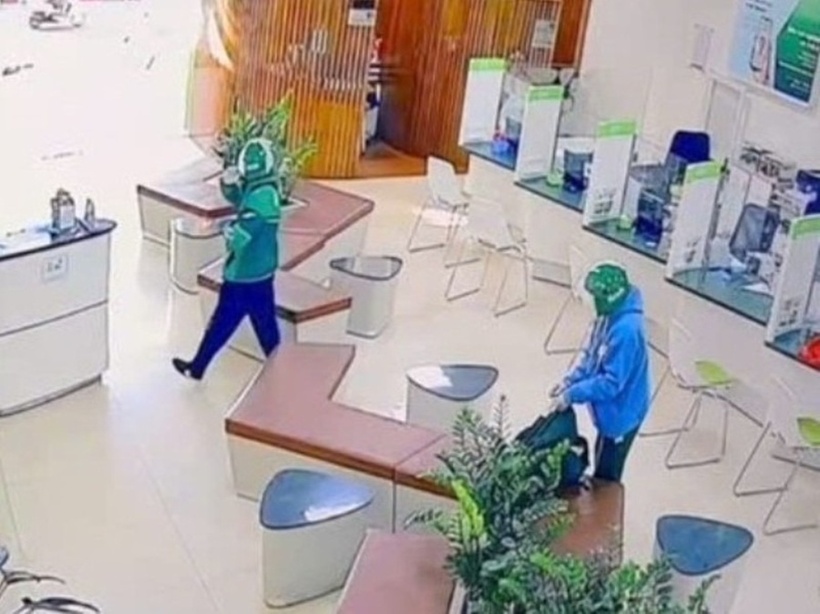 Hai đối tượng nam giới mặc trang phục áo khoác của hãng Grab, đội mũ bảo hiểm màu xanh Grab thực hiện vụ cướp ngân hàng. Ảnh: Vietnamnet.