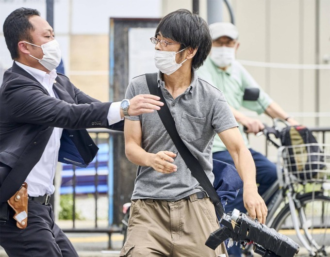 Yamagami cầm khẩu súng tự chế khi bị cận vệ của ông Abe (trái) lao tới khống chế. Ảnh: Kyodo.