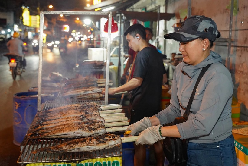 Người nướng cá liên tục trở tay, gõ nhẹ để loại bỏ lớp vảy và phần da cháy khét bên ngoài, giữ lại phần thịt bên trong chín vàng, thơm và không bị ám vị đắng.