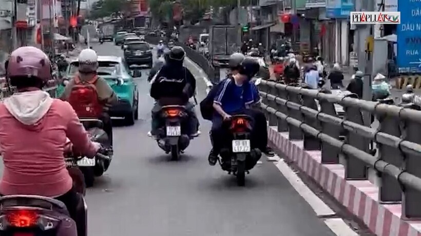 Nam sinh mặc đồng phục chở bạn lưu thông với tư thế "bất thường" trên đường phố. Ảnh: PLO.