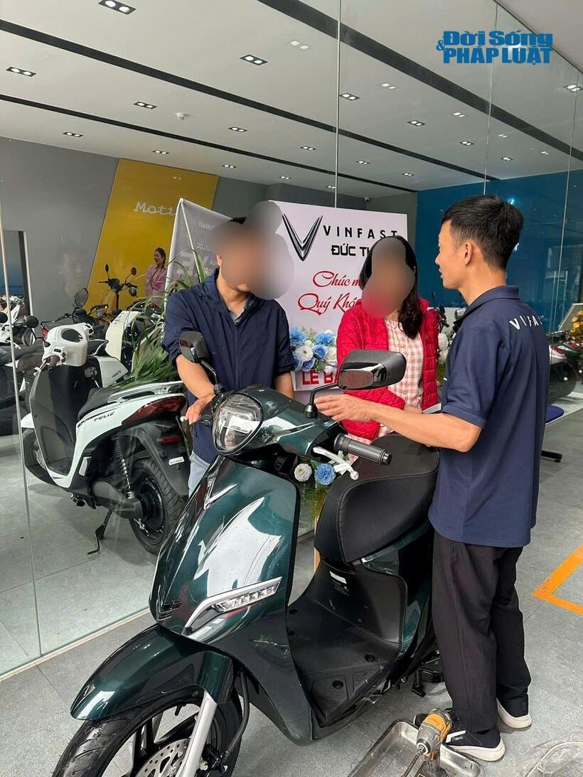 Nhân viên cửa hàng tư vấn cho khách hàng về thông số và giá bán của các dòng xe điện.