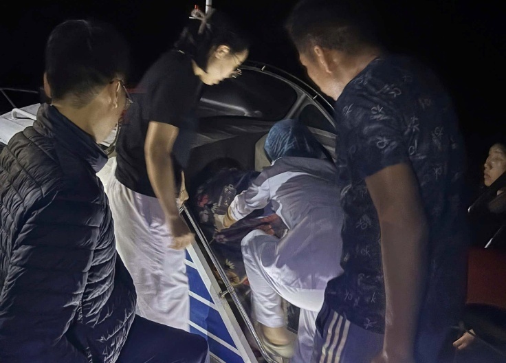 Ê-kíp y tế hỗ trợ đưa sản phụ vào đất liền. Ảnh: VietNamNet.